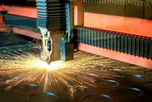 A machine cutting metal with sparks flying out of it.