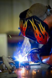 A person welding with flames on their helmet.
