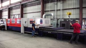 A man standing next to a machine in a warehouse.