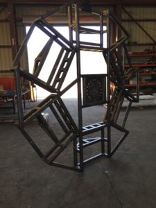 A metal sculpture of an octagon in the middle of a warehouse.
