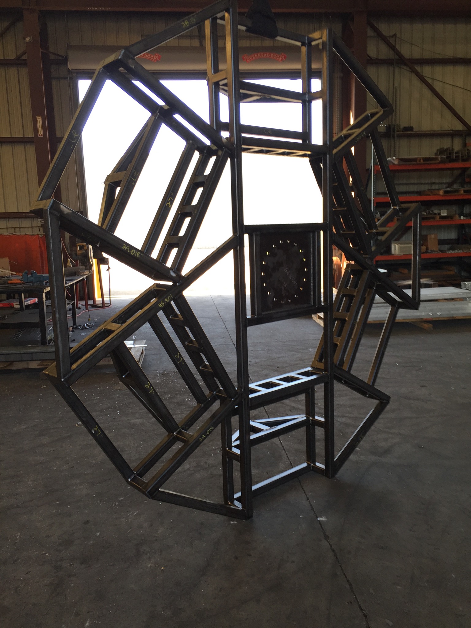 A metal sculpture of an octagon in the middle of a warehouse.